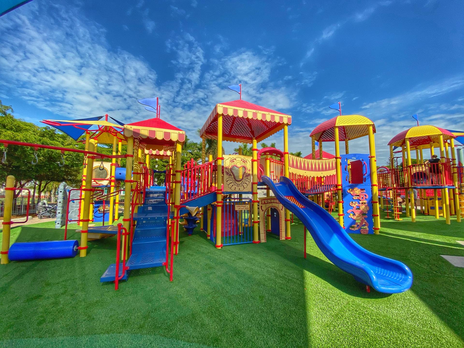 Circus theme playground at payne park its a sunny blue sky day and the primary color playground stands on a newly turfed ground.